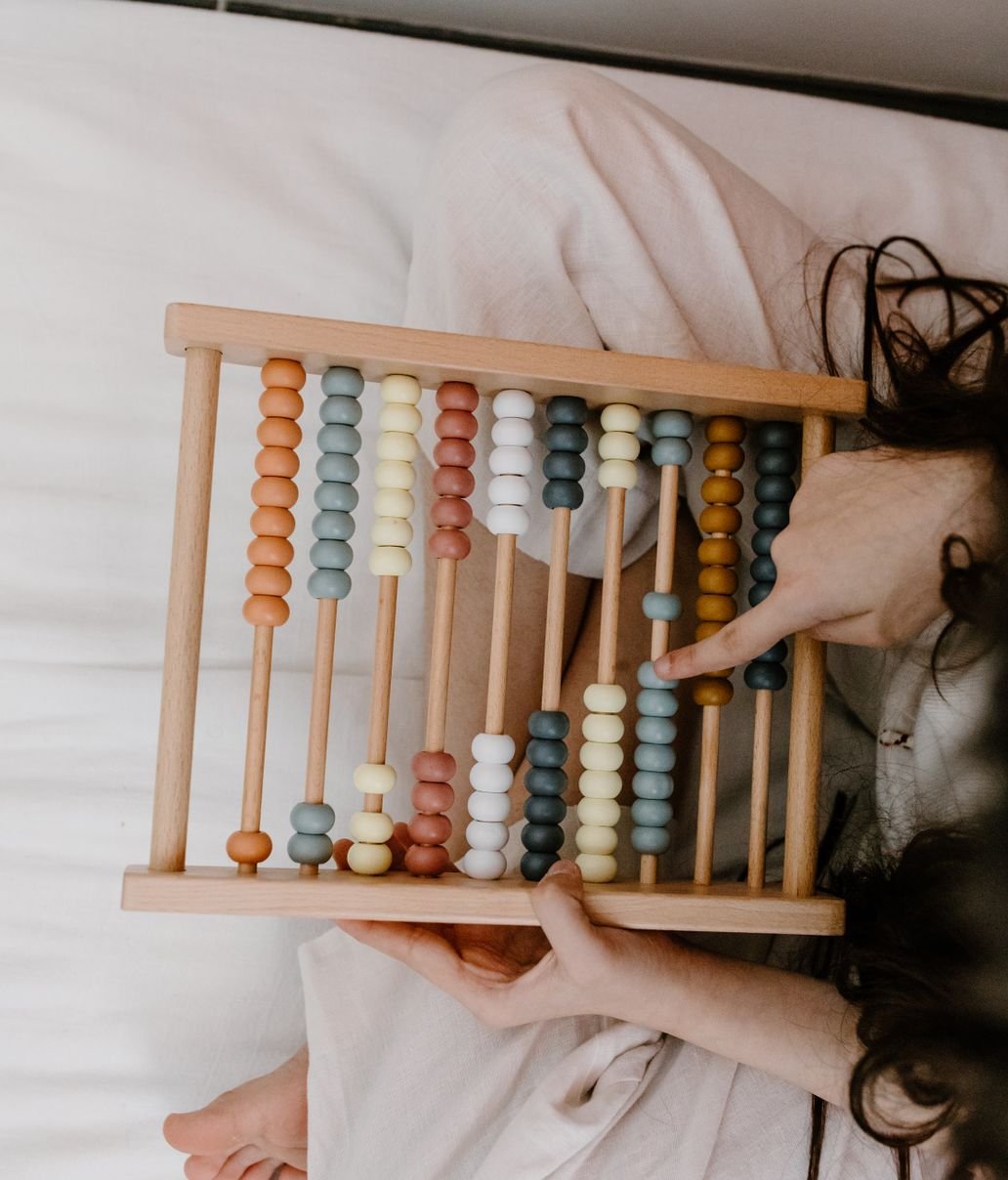 A child's hands moving the beads of a wooden abacus
