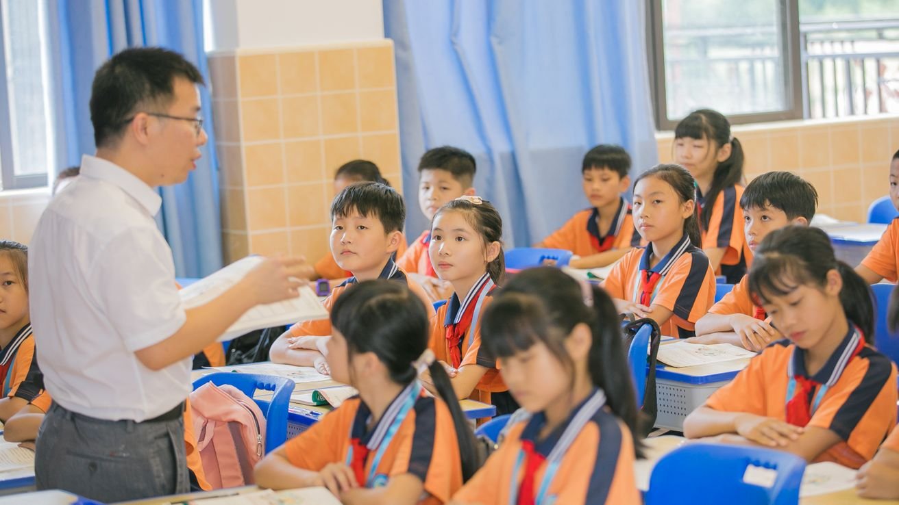 A teacher leading a class of primary school children at their desks