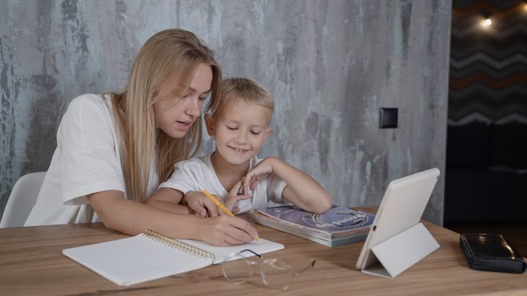 A parent and a young child practising together at the kitchen table.